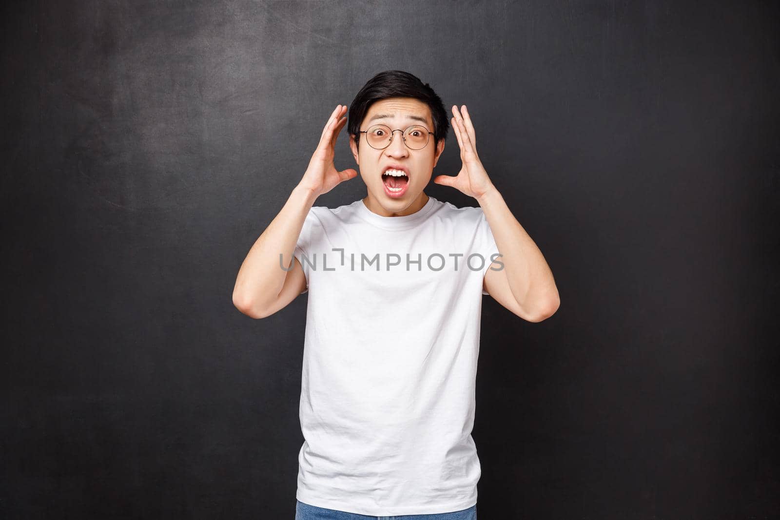 Alarmed and embarrassed young panicking asian guy, shaking hands near face as telling something shocking happened, retell outstanding story, staring camera, black background by Benzoix