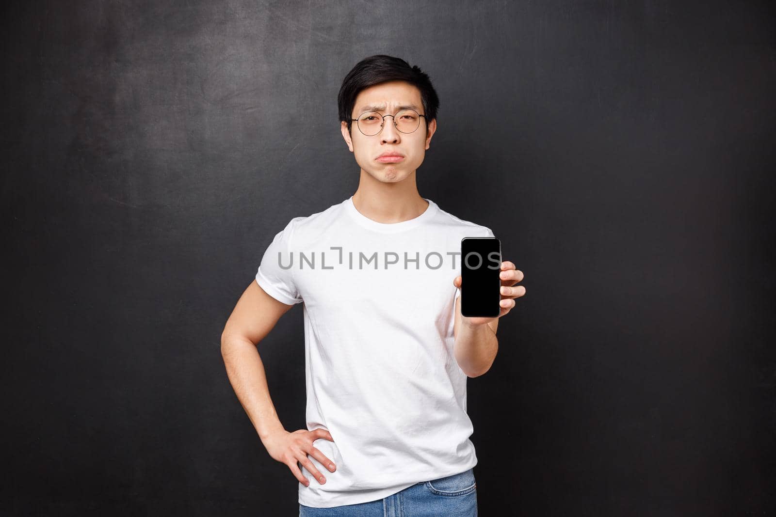 Technology, gadgets and people concept. Upset and gloomy cute asian guy complaining friends how girlfriend dumped him via message, showing text to you, mobile phone display by Benzoix