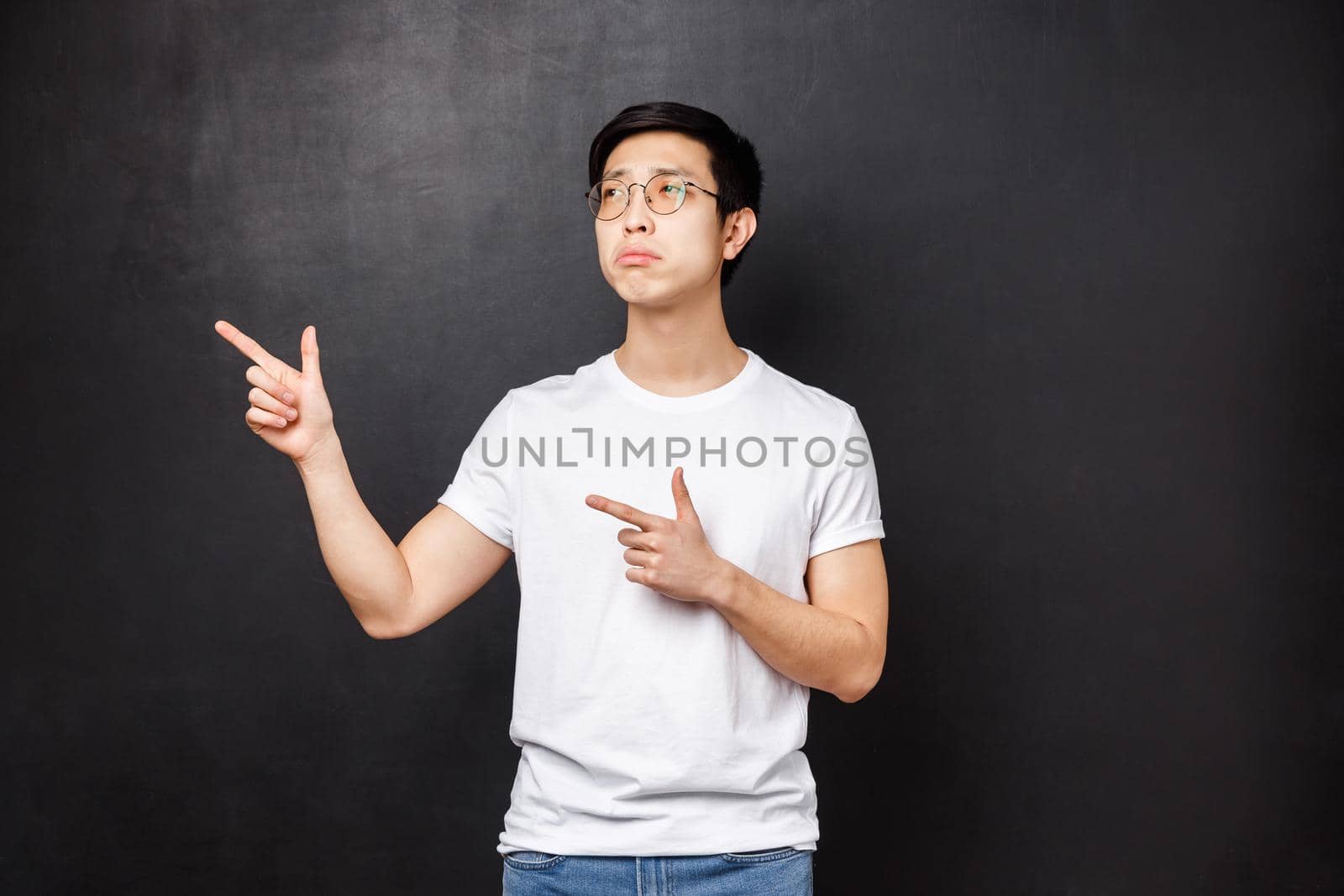 Portrait of distressed and upset gloomy handsome young guy missed chance to talk beautiful girl, pointing and looking left with regret and uneasy feeling, let go, black background.
