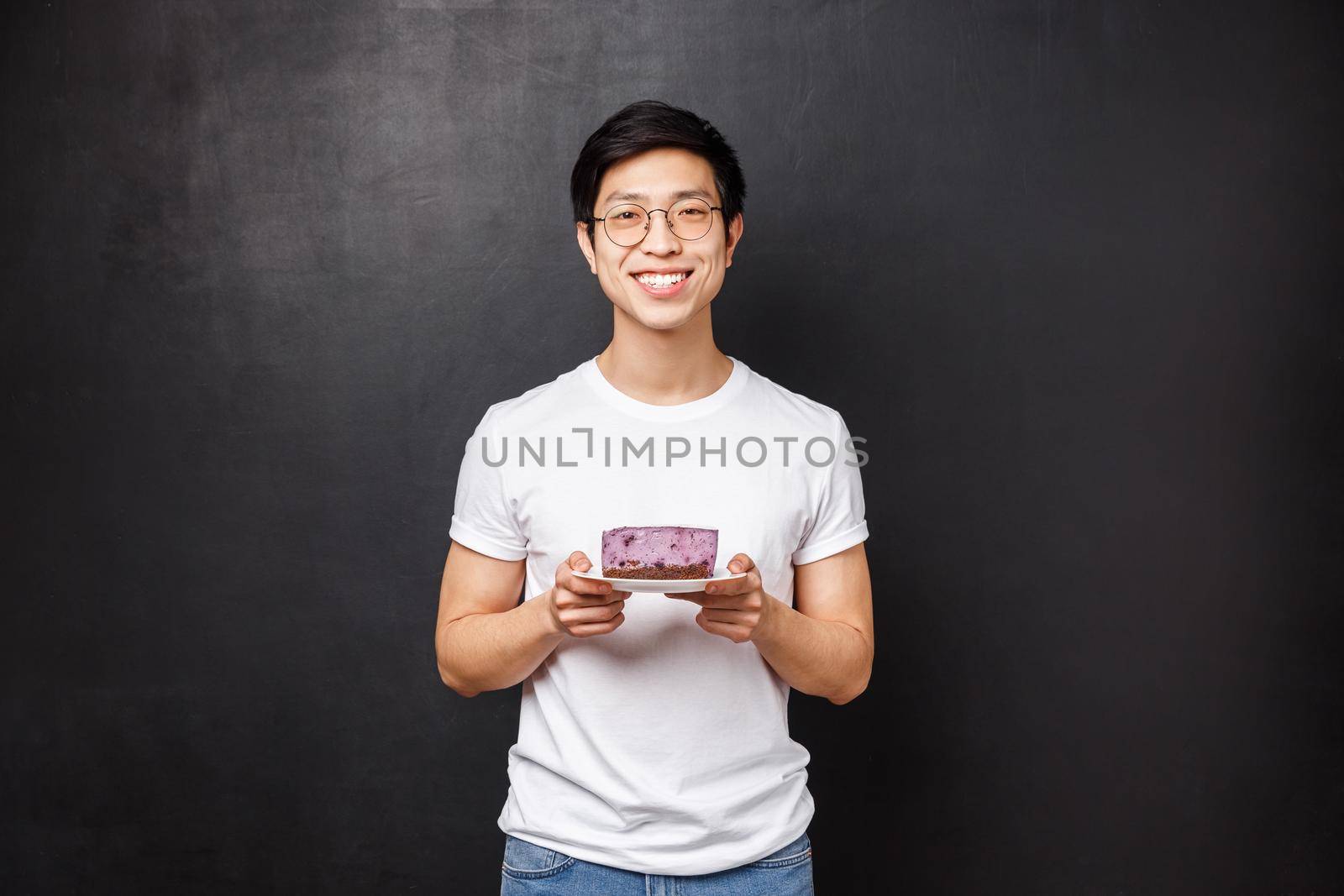 Portrait of cheerful caring handsome asian boyfriend bring piece of tasty cake for girlfriend, trying take care and do nice lovely gesture express sympathy, standing black background by Benzoix