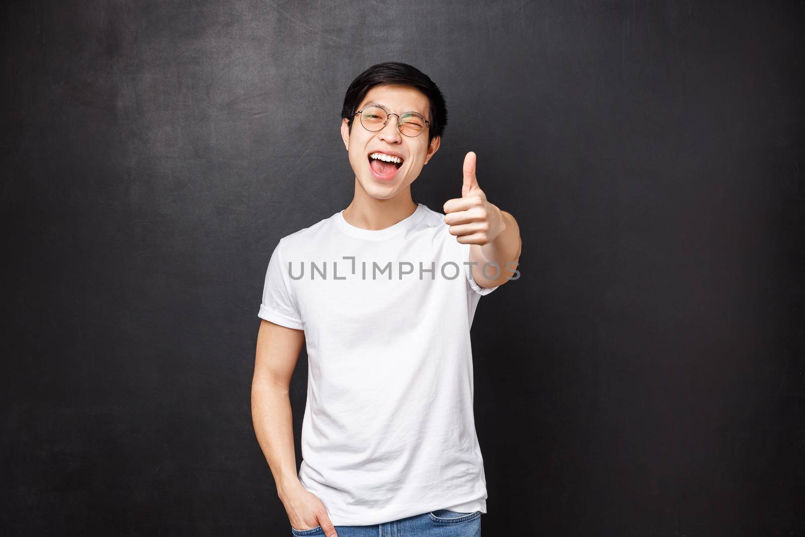 Lifestyle and people concept. Happy and satisfied young asian modern guy customer left impressed and pleased after attending awesome concert, show thumb-up in approval and wink joyfully by Benzoix