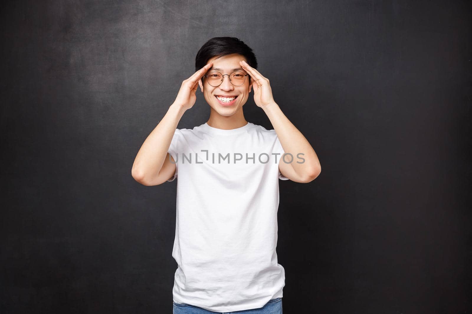 Happy charismatic young man feel well, got better after having prescribed medicine, smiling camera and hold hands near forehead as if seeing something distance, found perfect spot by Benzoix