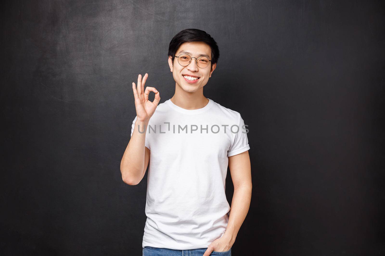 Portrait of handsome smiling young modern asian male student in sunglasses and t-shirt, confirm or guarantee perfect quality, show okay sign, agree with person, like product by Benzoix