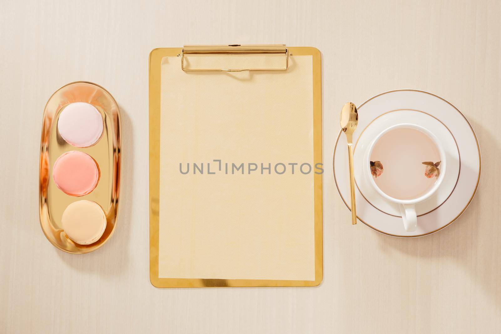 Women's home office workspace with clipboard, macaroons, pen, coffee mug on pastel background. Flat lay, top view lifestyle concept.