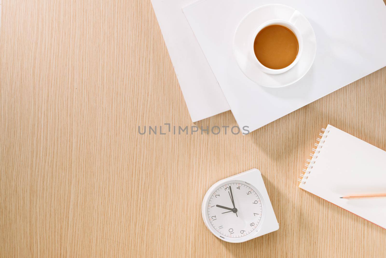 Flat lay of coffee cup, clock, pencil and a notebook. 