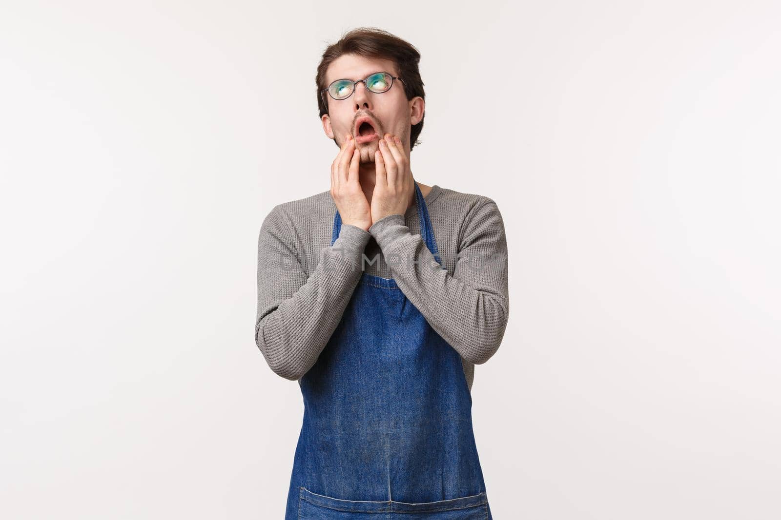 Portrait of distressed and bothered caucasian male coffee shop barista feel sick and tired of working overtime, sighing and look up, facepalm displeased, standing white background upset.