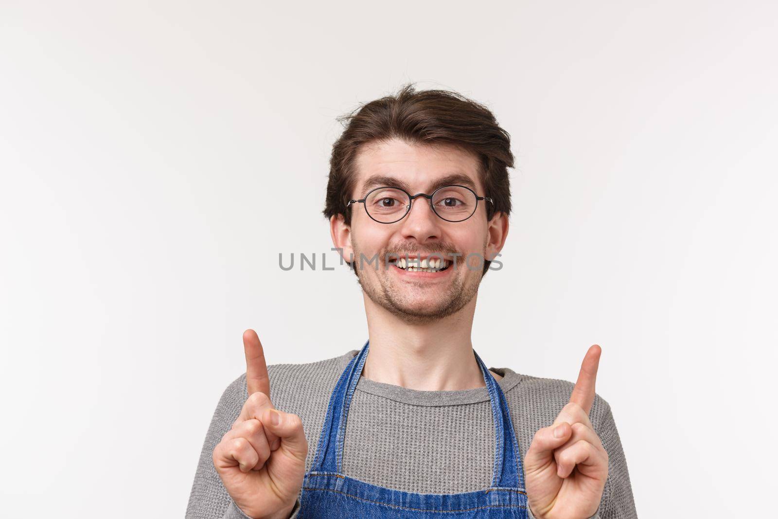 Advertisement, small business and career concept. Close-up portrait of friendly young guy employee working in coffee shop, happy inviting people try best drink in town, pointing up.