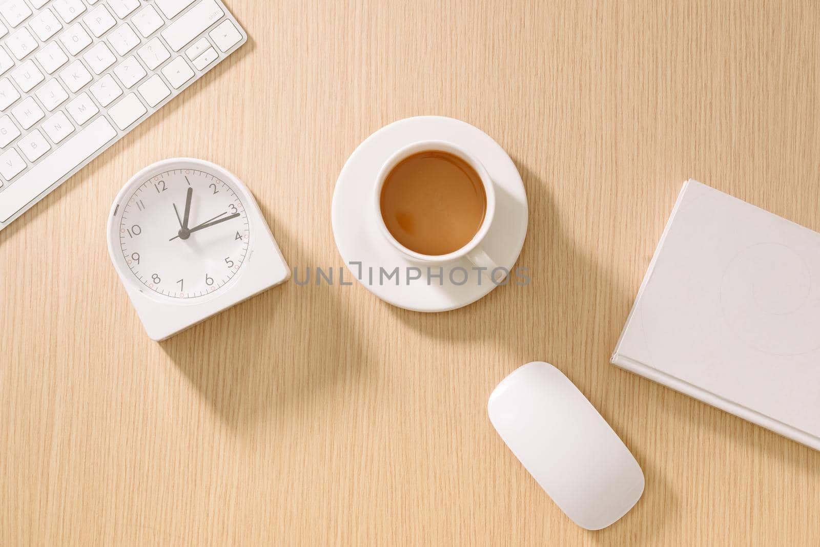 Modern white office desk with keyboard, mouse, notebook, clock and cup of coffee. Top view with copy paste. Business and strategy concept mockup.