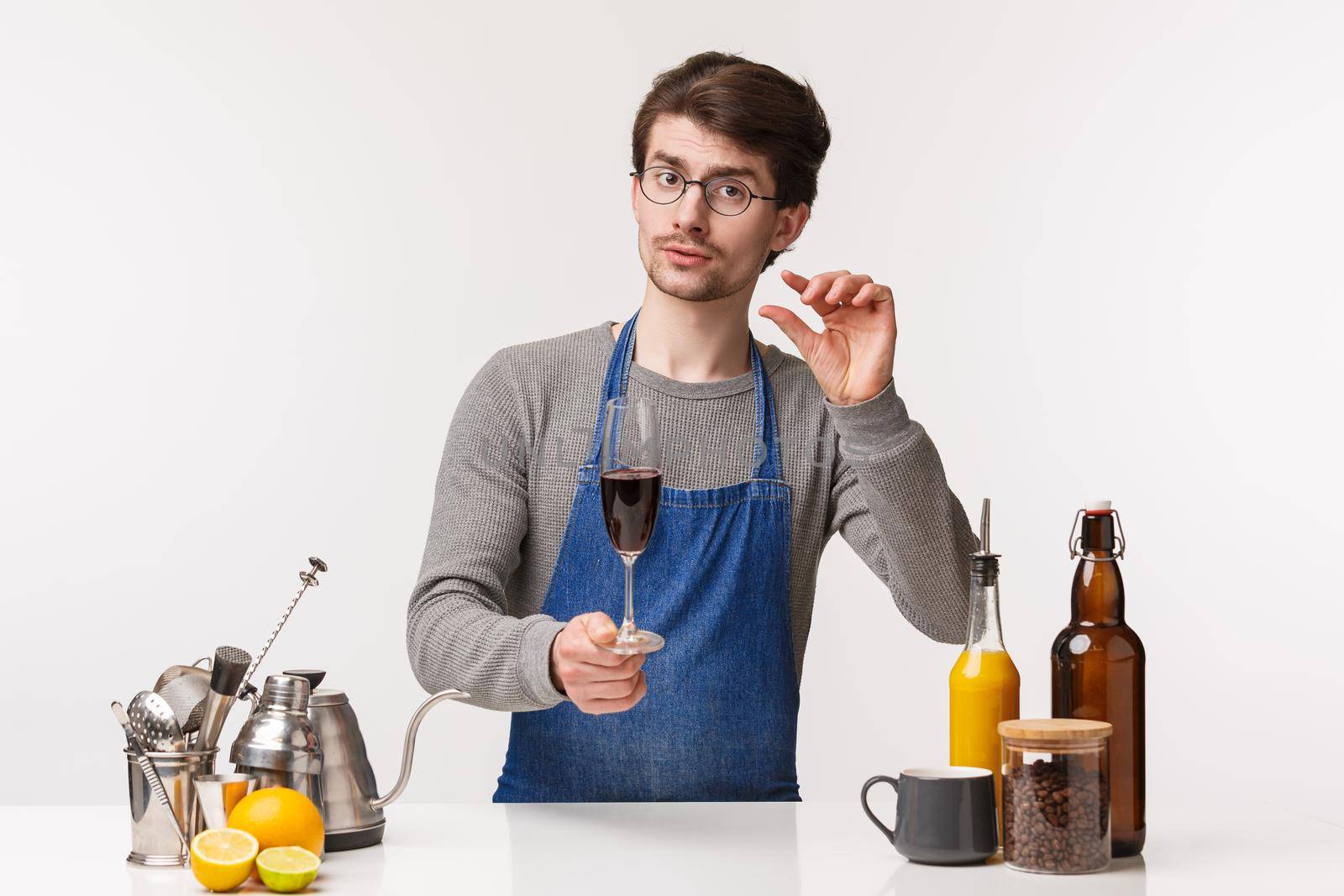 Barista, cafe worker and bartender concept. Professional good-looking male employee pouring glass of wine recommend drink little for good health, standing near bar counter, white background.
