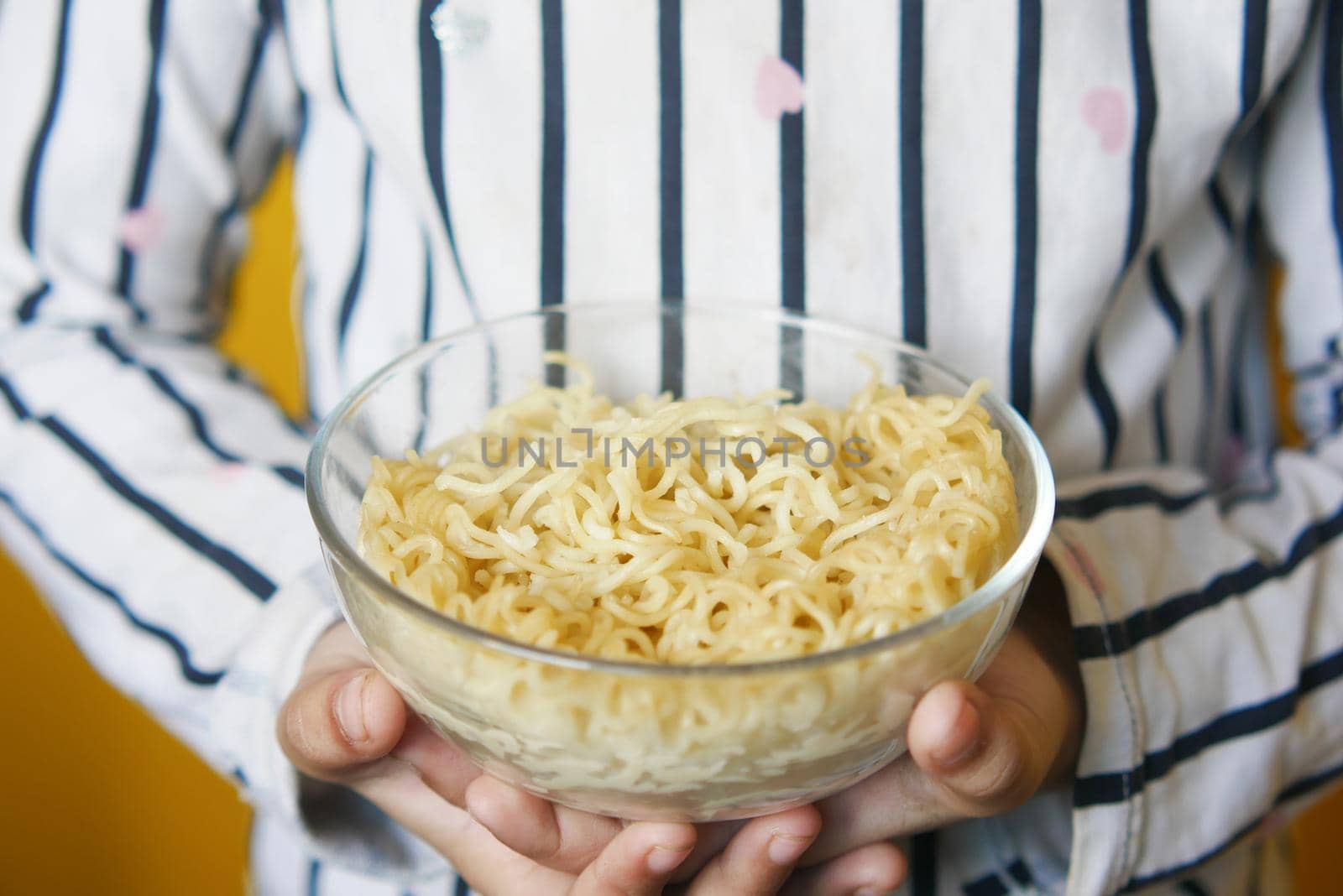 boy eating noodles in a bowl .