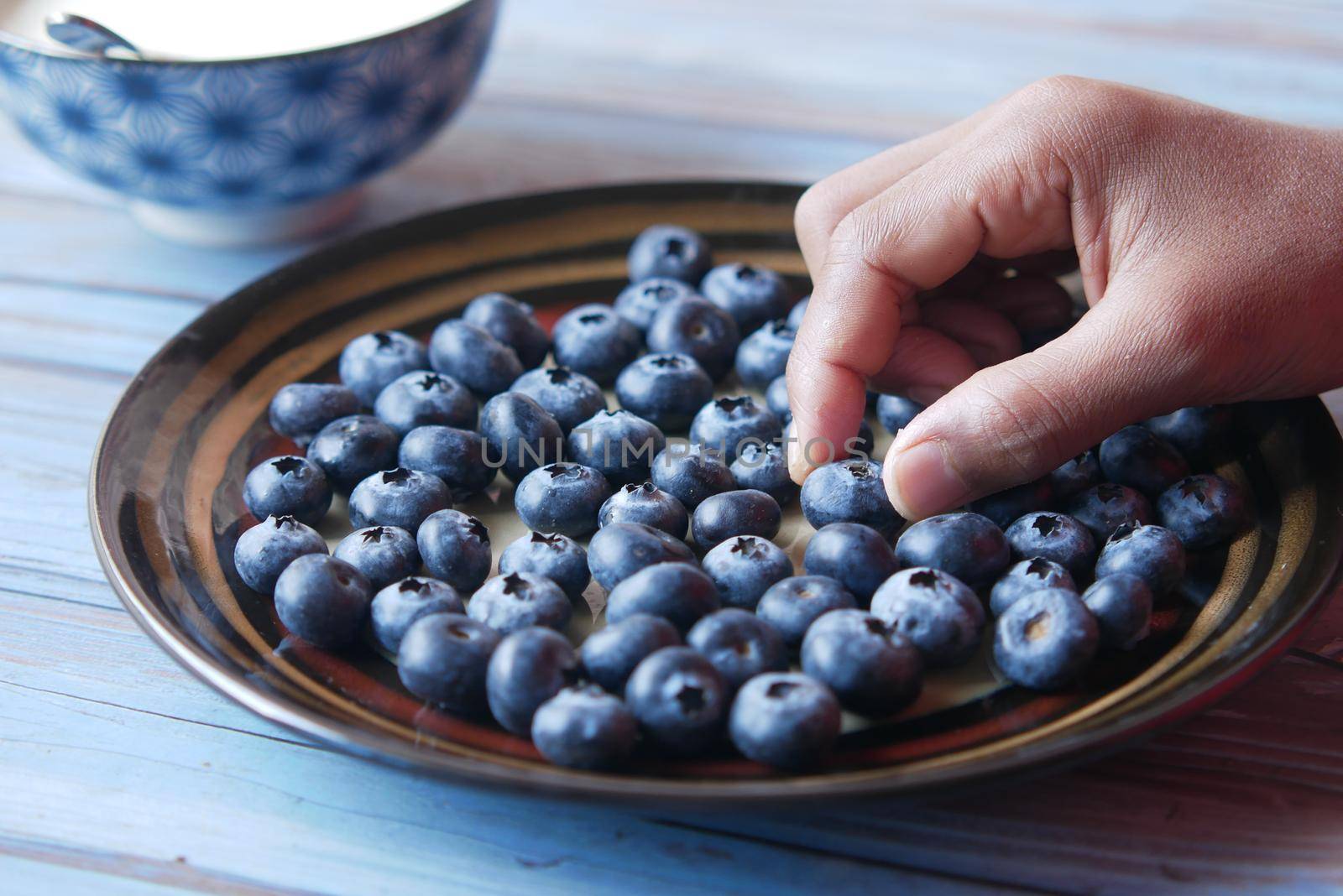 hand pick fresh blue berry from a plate .