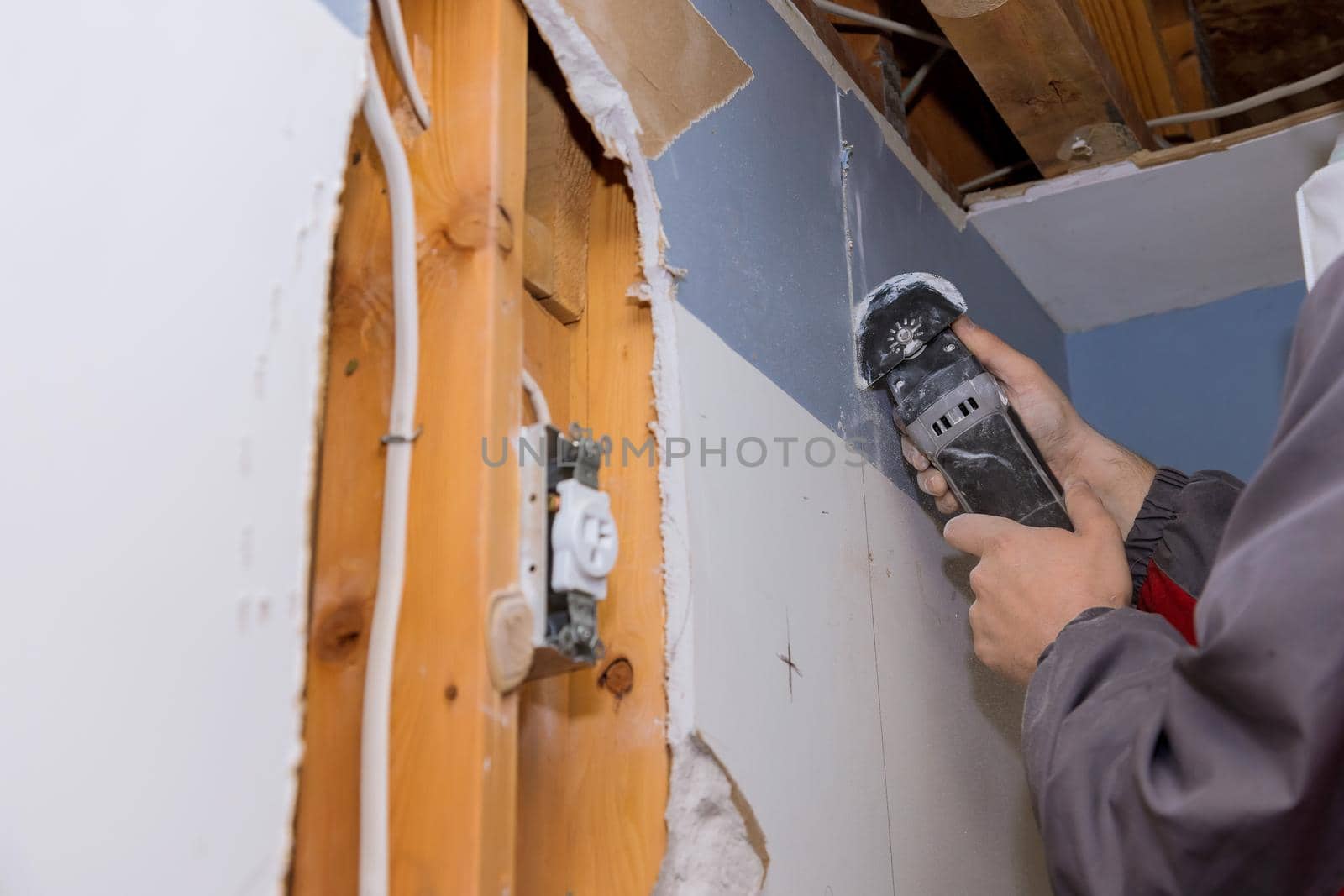 Home renovation service repair works of replacement damaged drywall on worker cutting plasterboard with construction electric power tools