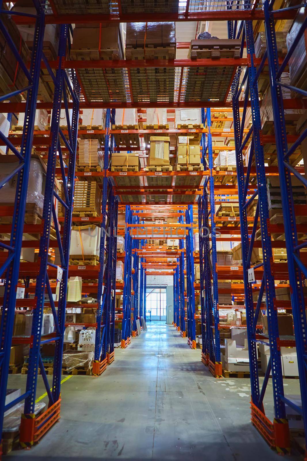 Interior of a modern warehouse storage of retail shop with pallet truck near shelves by sarymsakov