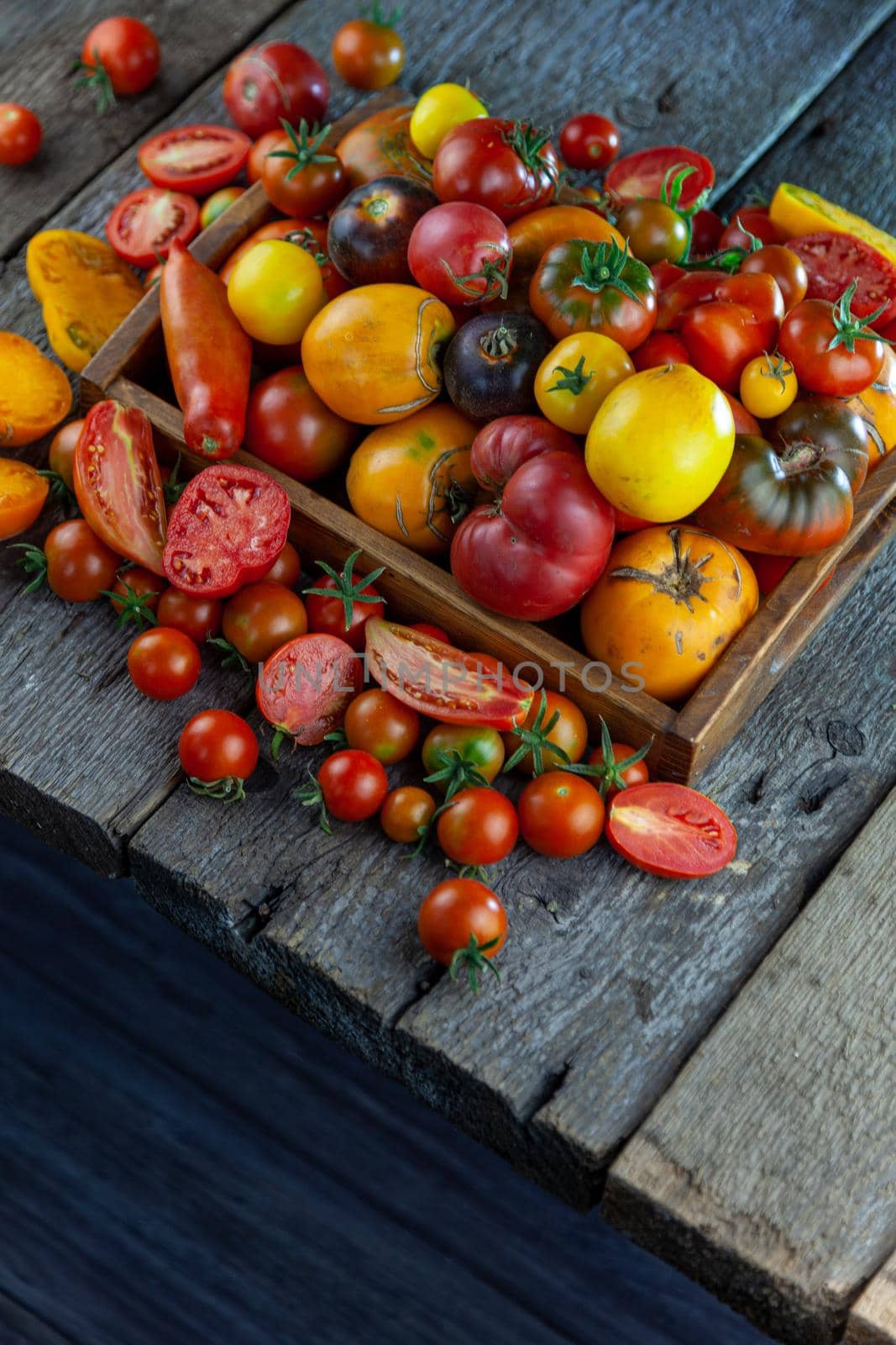 Tomatoes of different varieties and colors top view. Layout on a wooden background. Food. Sliced tomato, ingredients for salad. Place for text. Yellow and red cherry. Copy space. by A_Gree