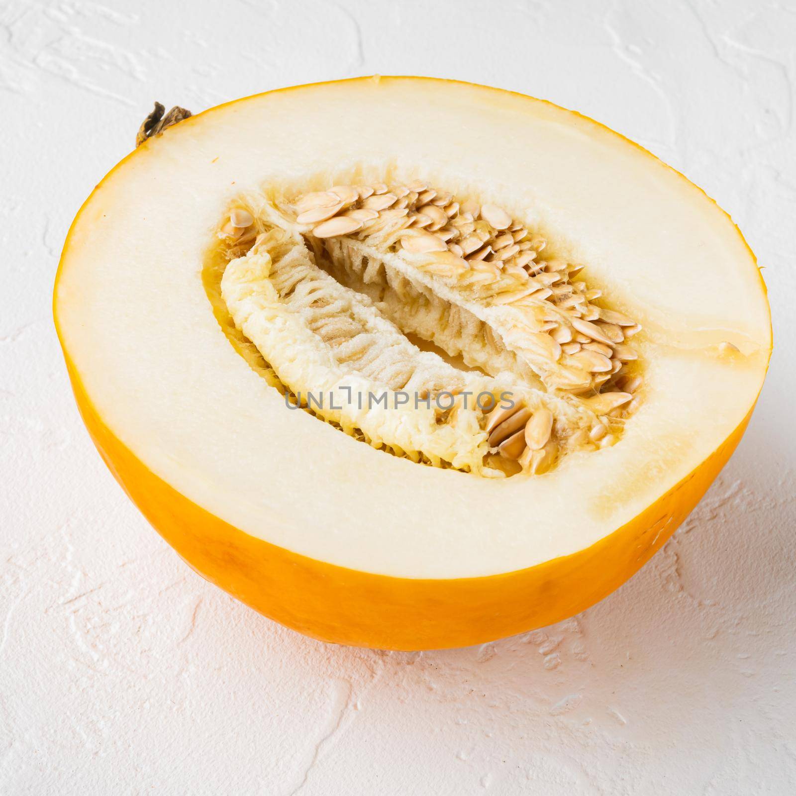 Sugar melon cut in half set, on white stone table background, square format