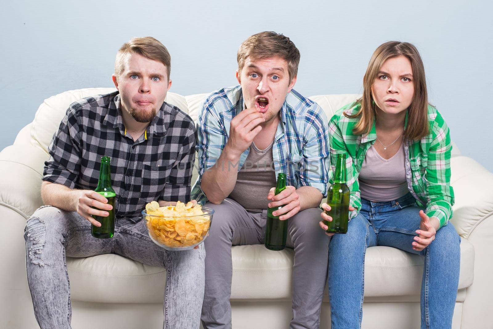 Young men drink beer, eat pizza and cheering for football