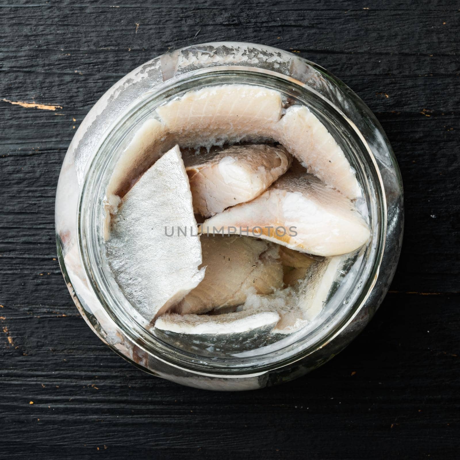 Canned Herring , fish preserves set, in glass jar, on black wooden table background, top view flat lay, square format