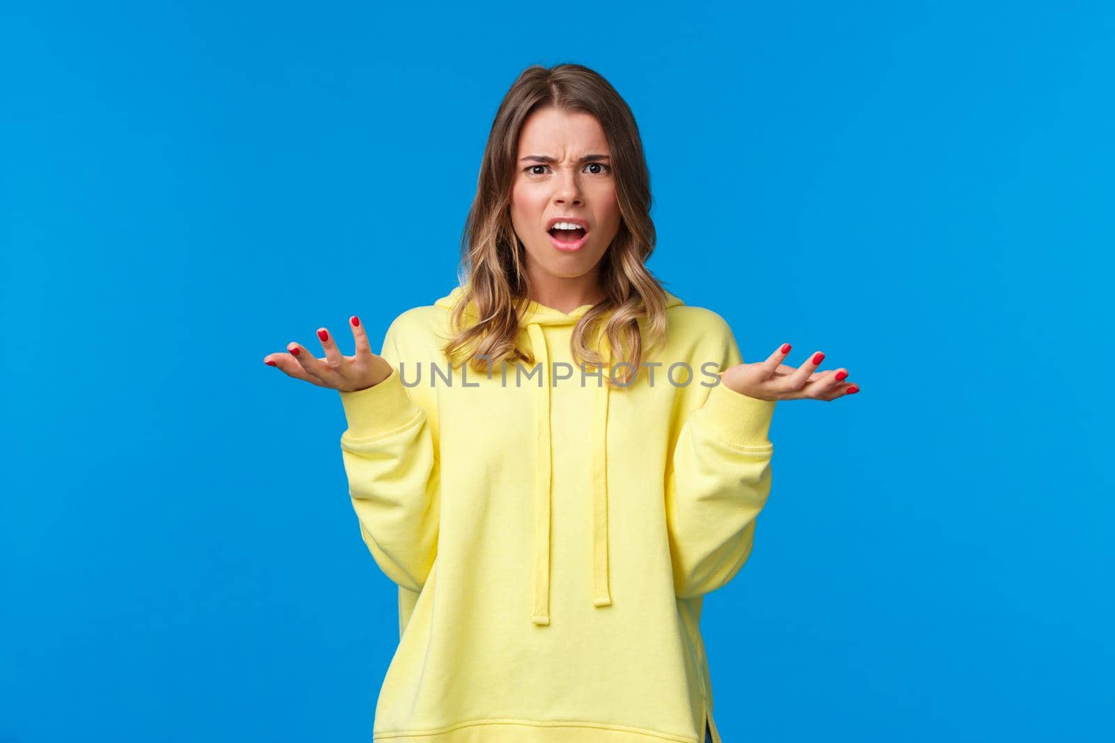 Frustrated and displeased confused young blond girl shrugging, looking at camera with disagreement and bothered expression, hear nonsense, have argument cant understand what happening.