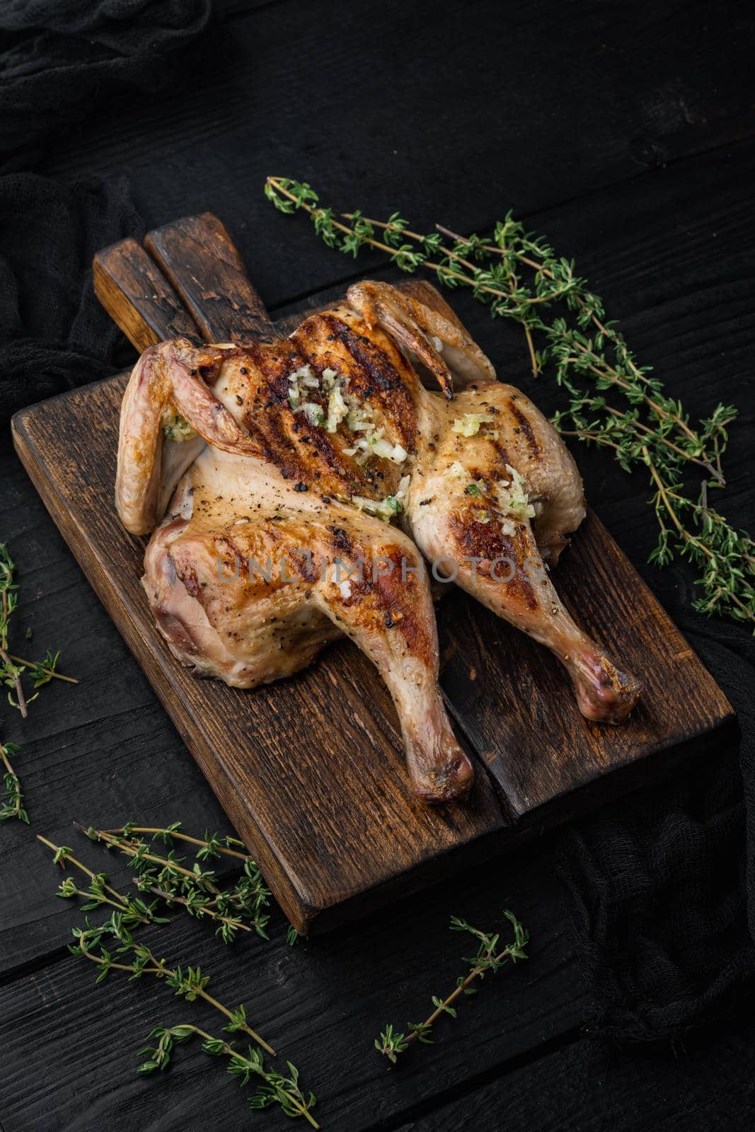Spatchcocked poussins, with chimichurri sauce, on black wooden background