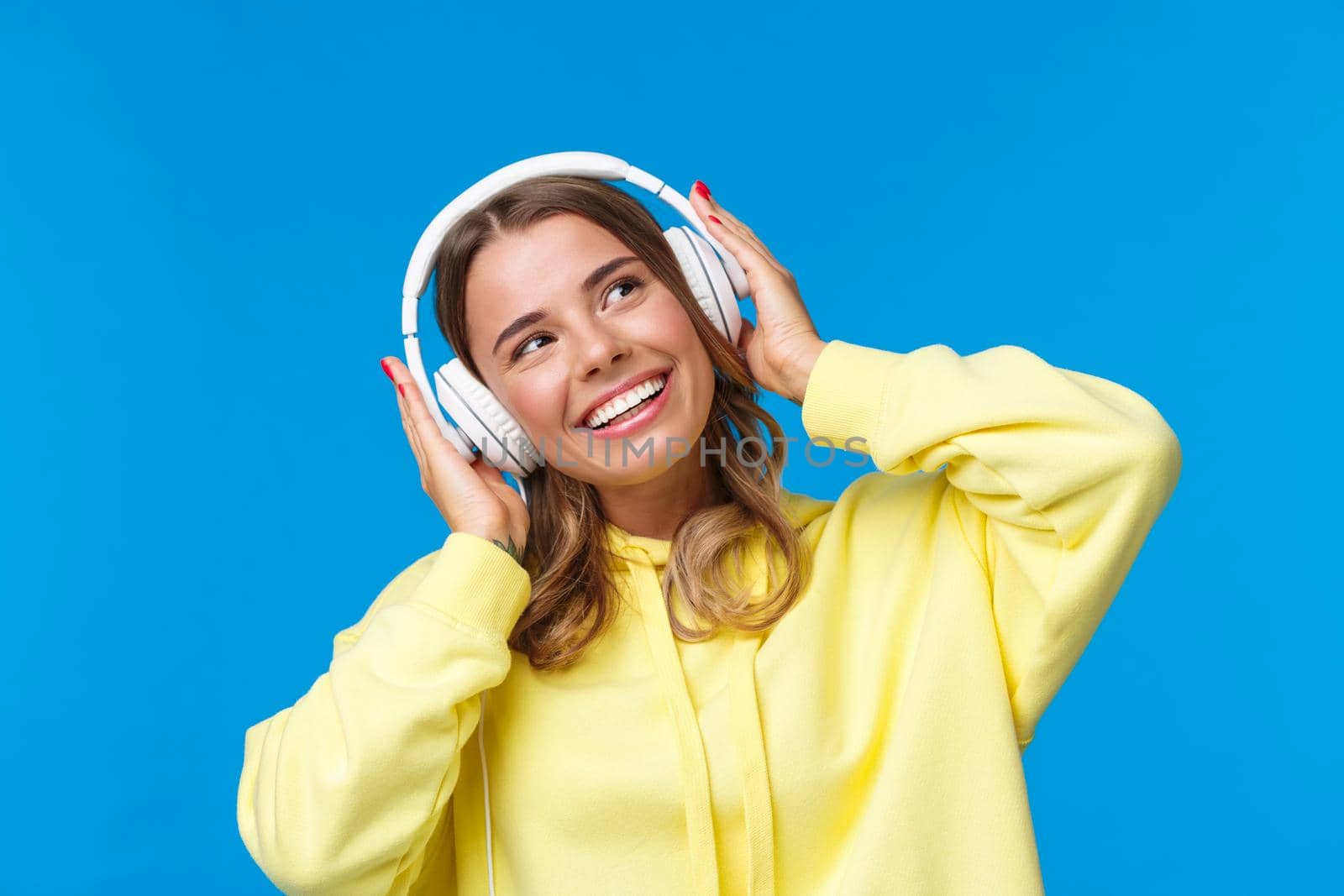 Music, lifestyle and youth concept. Close-up portrait dreamy good-looking cute blond girl with short haircut, listening songs, favorite playlist in headphones, dancing looking up smiling pleased by Benzoix