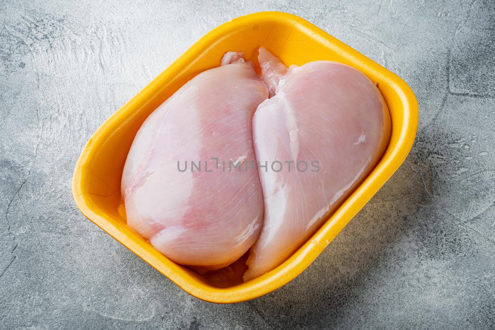 Raw chicken breast fillets in tray, on gray background