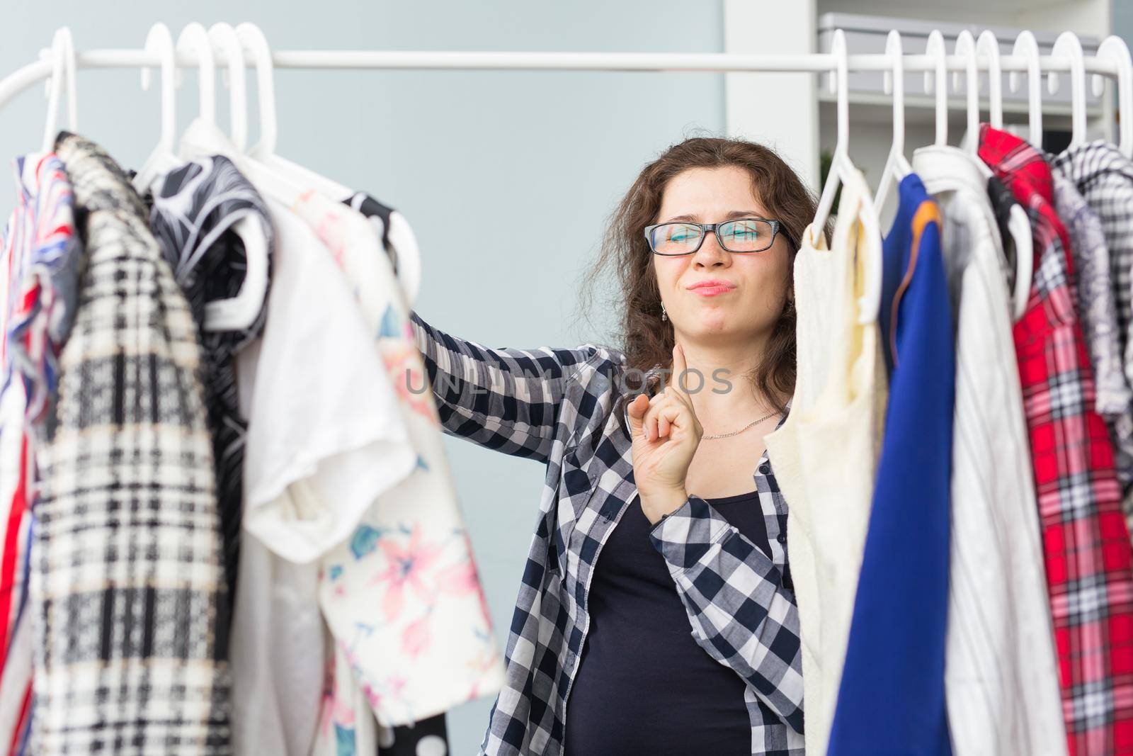 people, clothing and style concept - portrait of a pretty woman looking through the wardrobe.