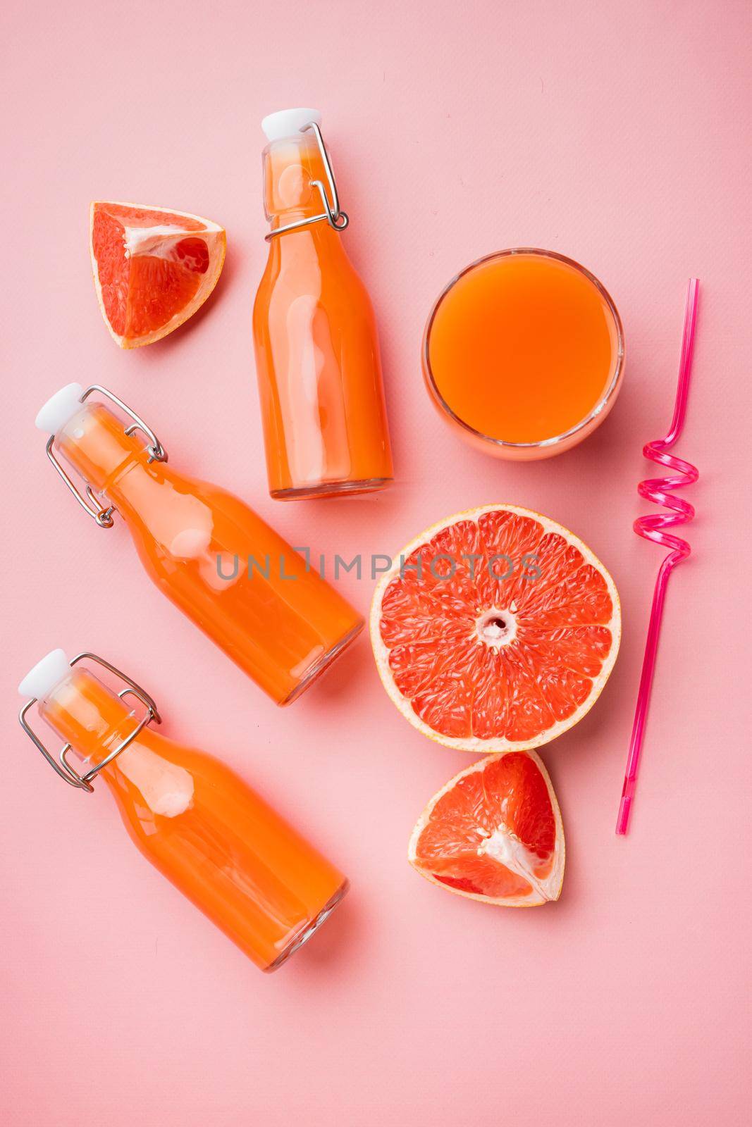 Ripe grapefruit with juice set, on pink textured summer background, top view flat lay