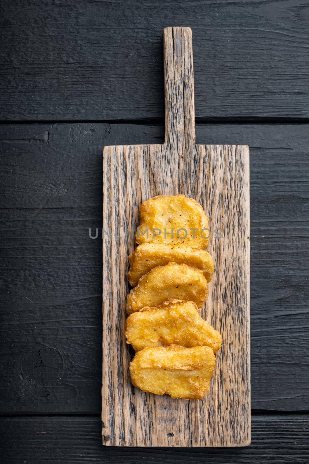 Fried crispy chicken nuggets meat on black wooden background, flat lay.