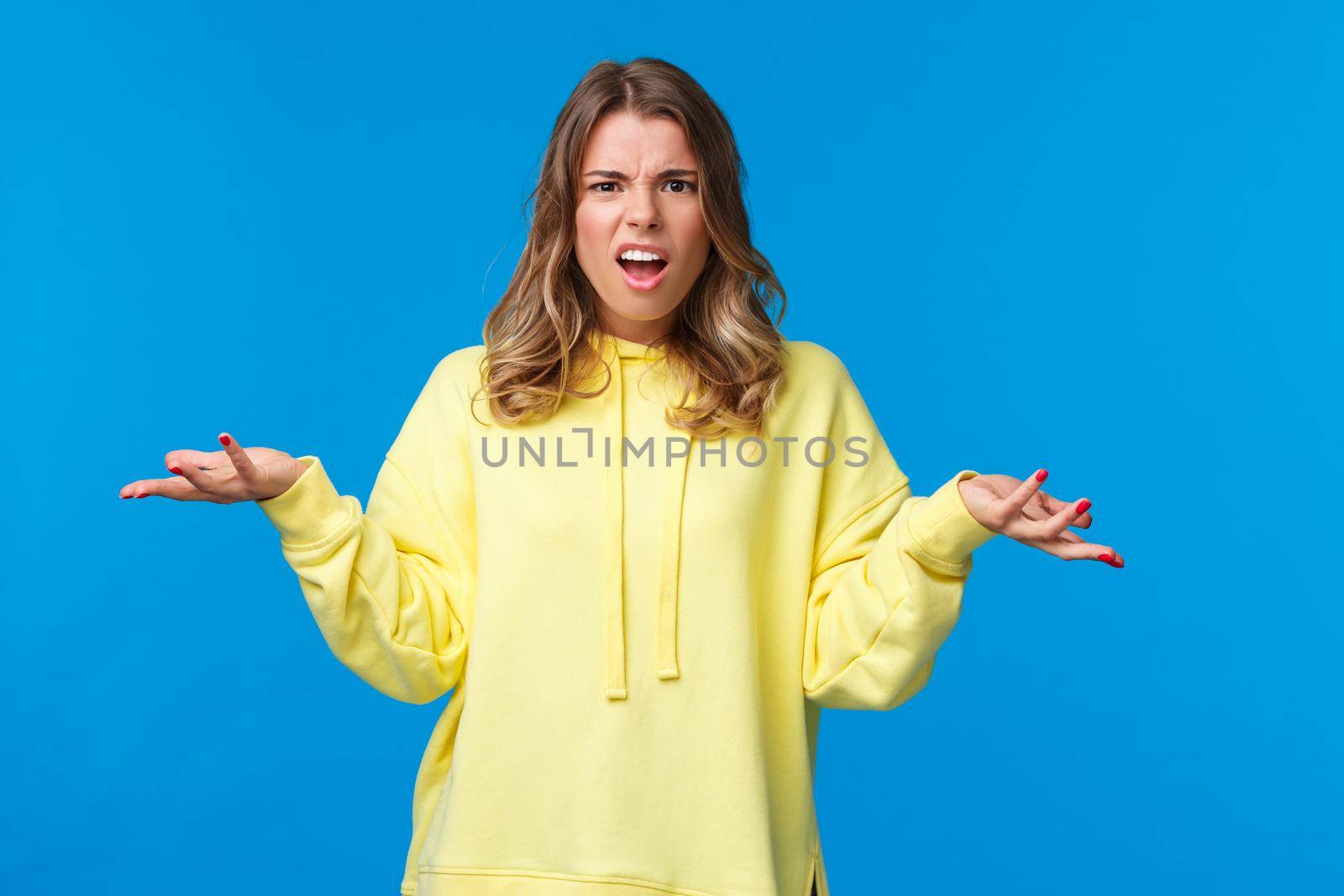 What a heck. Angry and frustrated young woman arguing with person being rude for no reason, shrugging with hands spread sideways in dismay, stare pissed-off and questioned, clueless about problem by Benzoix