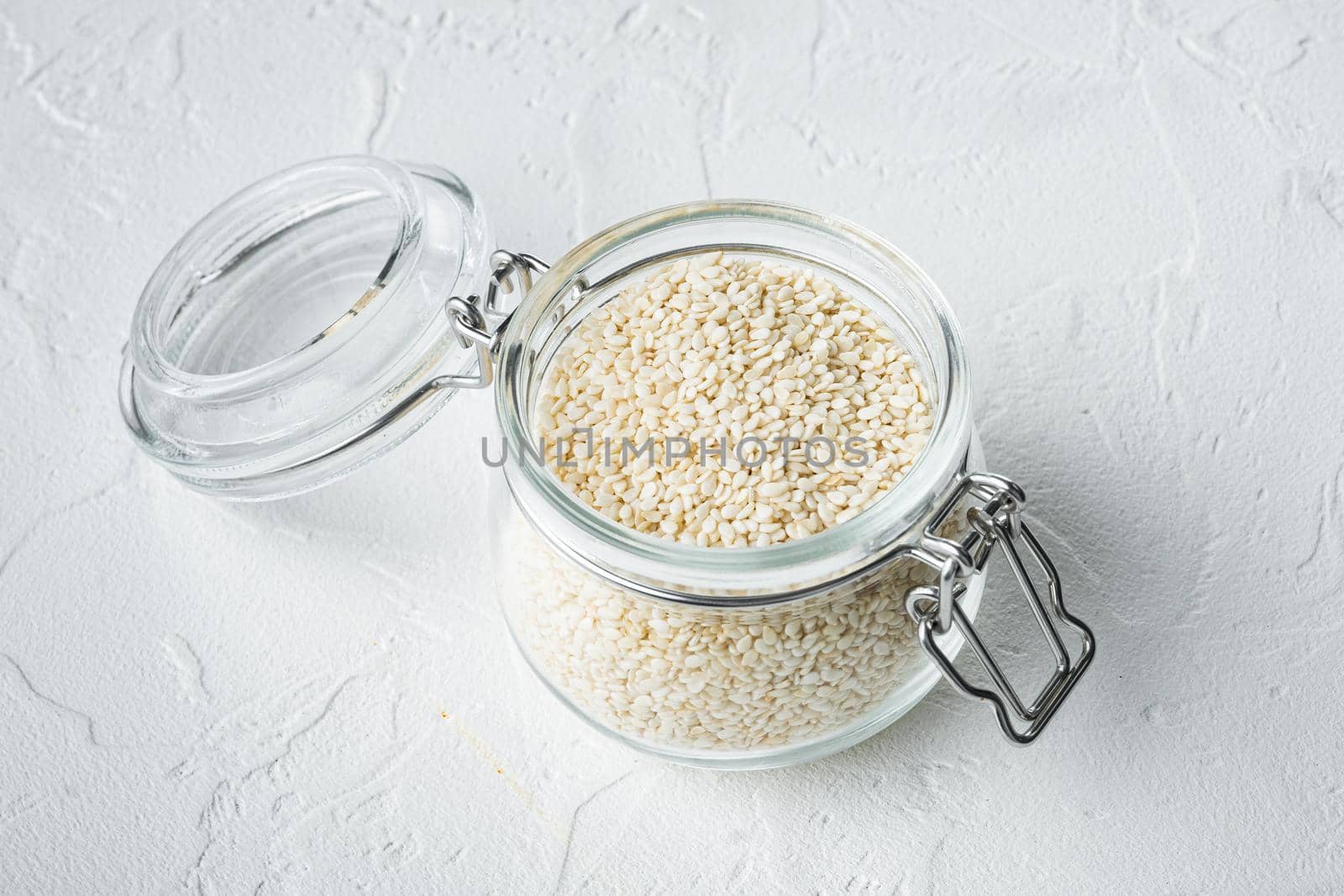Organic natural sesame seeds set, in glass jar, on white stone background