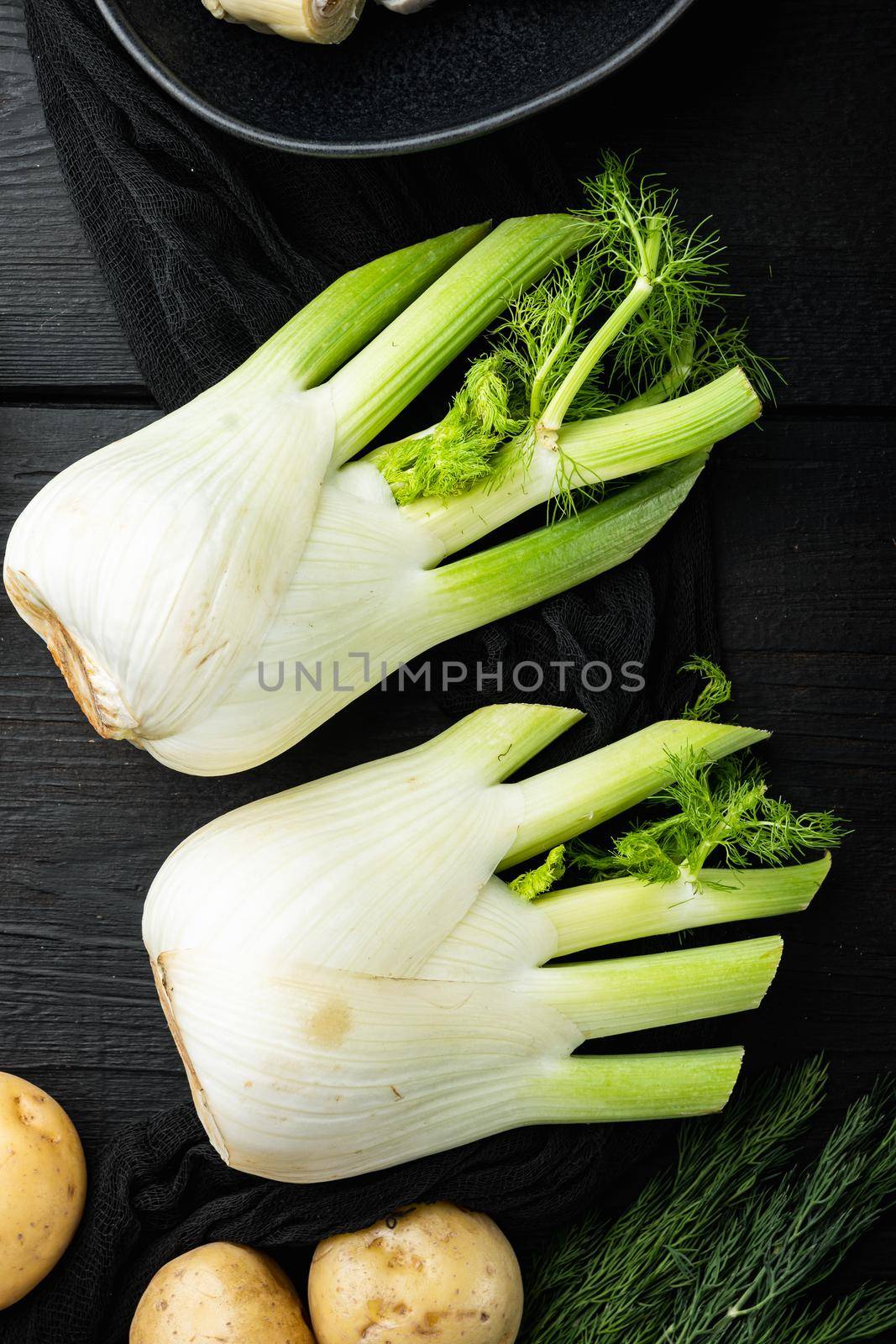 Fresh florence fennel bulbs, on black wooden table, top view by Ilianesolenyi