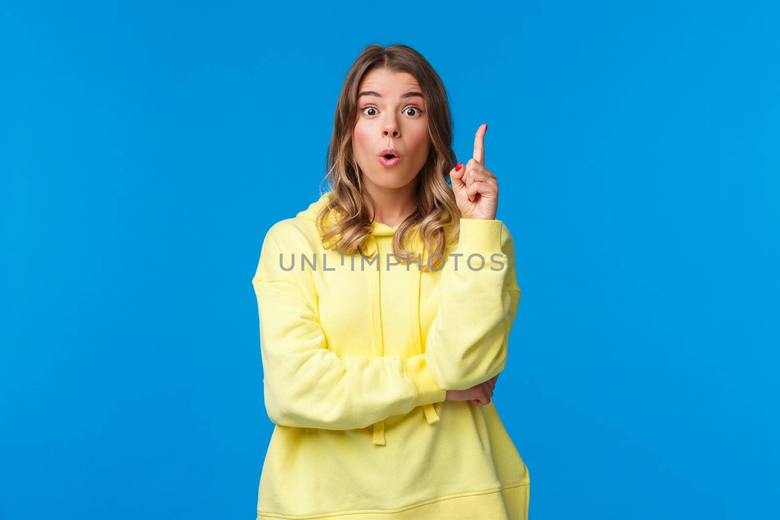 Got an idea. Excited creative and smart blond caucasian woman have suggestion, show eureka gesture with index finger raised up, talking to team, made-up plan, stand blue background.