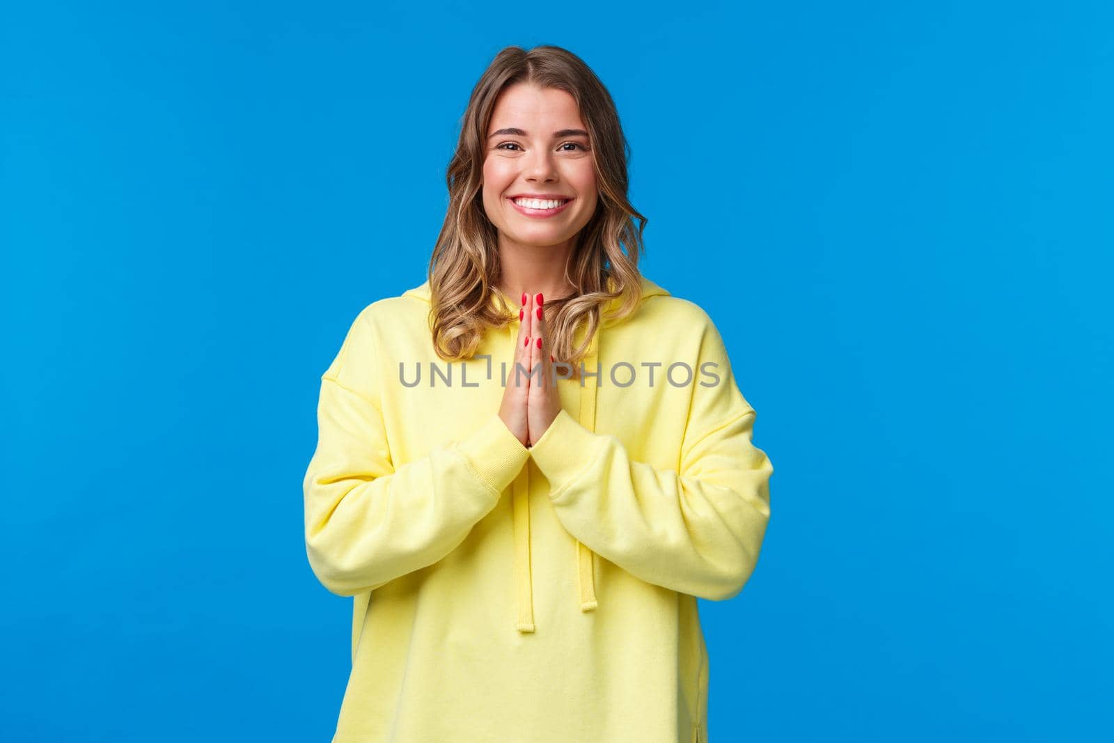 Cheerful young european female practice yoga, greeting sensei with namaste gesture, hold hands in pray and smiling grateful with relaxed carefree expression, smiling camera, blue background.