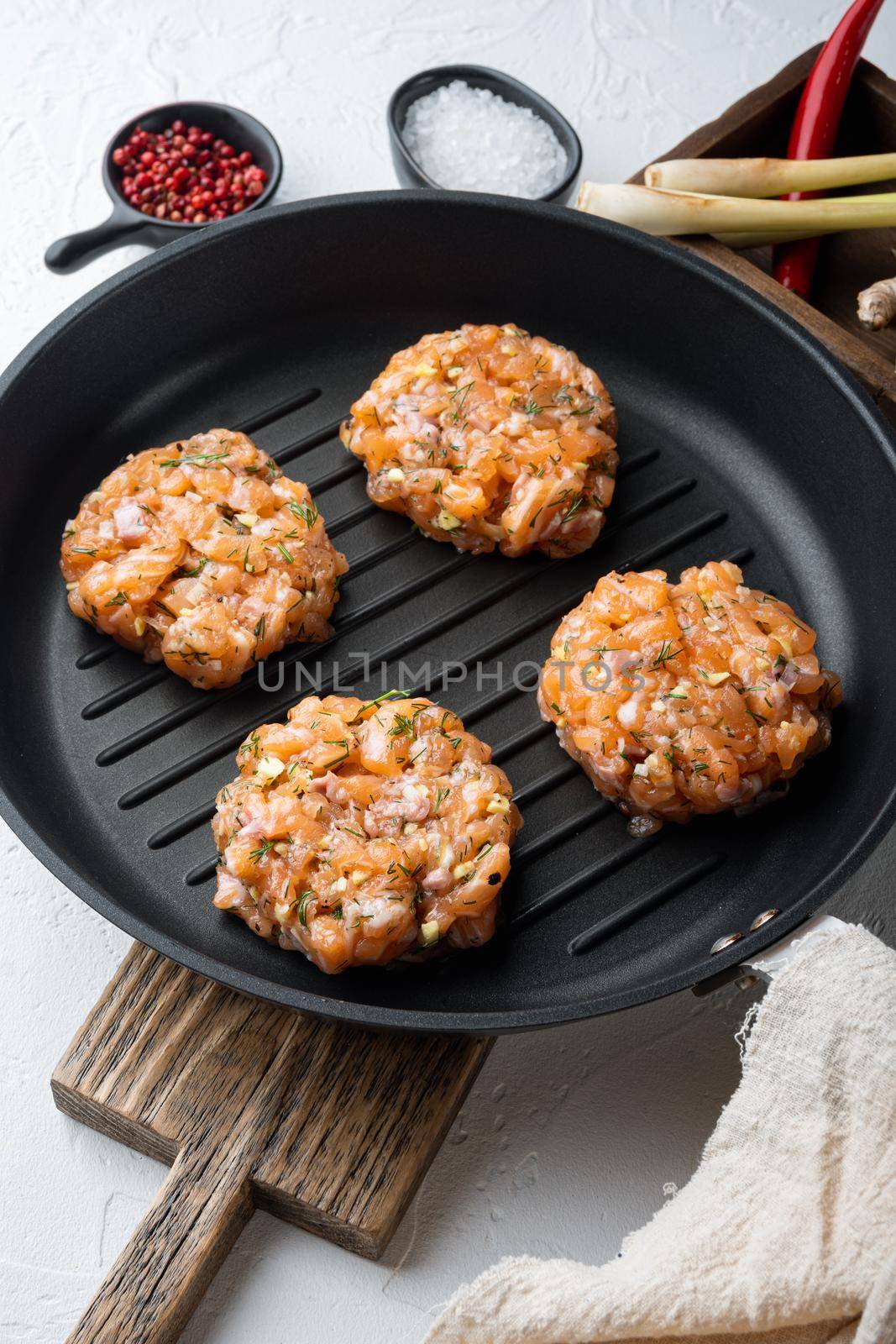 Raw fish patties with salmon fillet and lemongrass, on white textured background