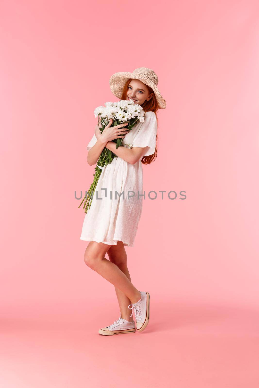 Full-length vertical shot lovely, romantic and happy redhead girlfriend in straw hat, cute dress, hugging big beautiful bouquet, smelling flowers and smiling, blushing from receiving gift.