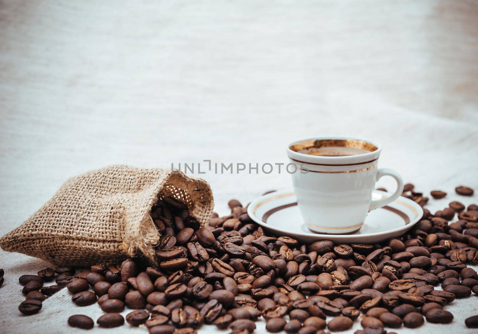 Coffee cup and beans on a biege burlap background. roasted coffee beans