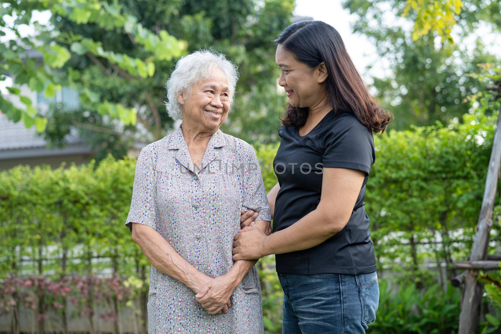 Asian elderly woman with caregiver daugther walking and hug with happy in nature park.