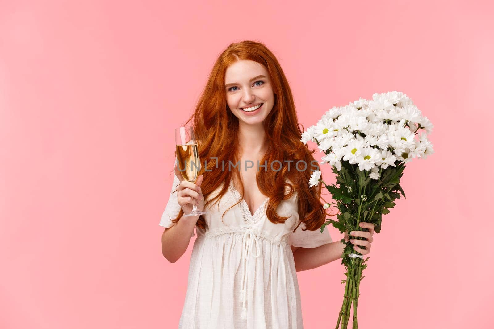 Women day, romantic moments and relationship concept. Charming, alluring caucasian redhead girl raising glass of champagne in cheers gesture to celebrate, hold bouquet flowers.