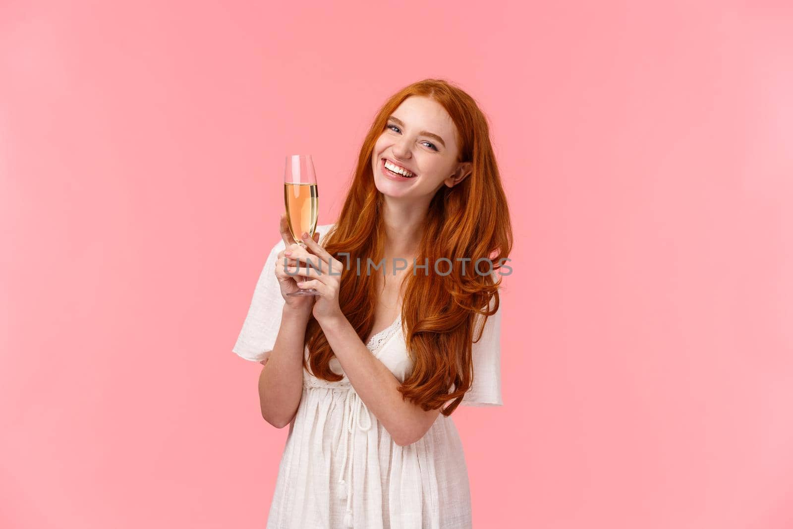 Carefree, excited cute redhead woman celebrating birthday, attend fancy party, wear white dress, laughing as discussing something with friends, raising glass champagne, drinking for success.