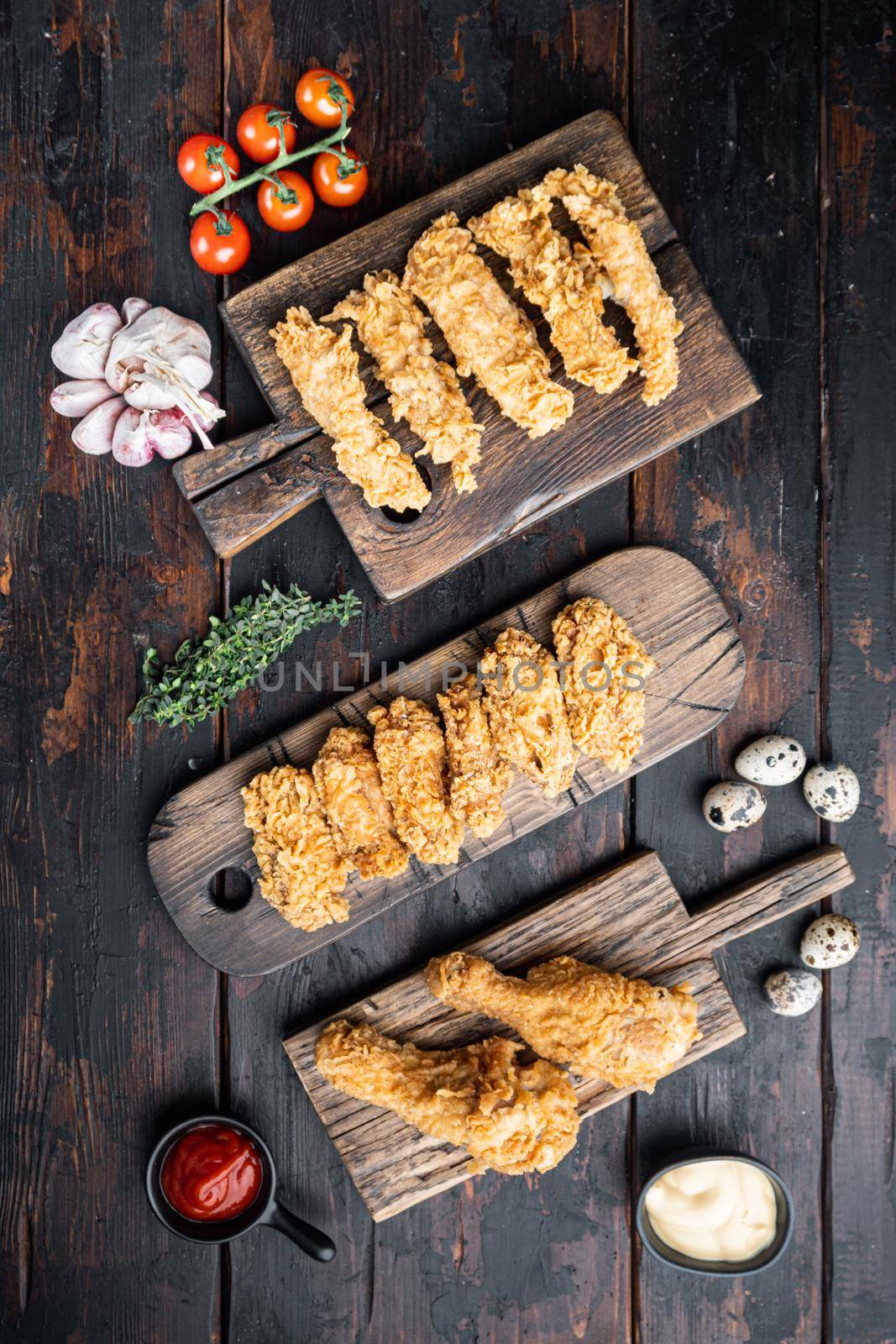 Homemade crispy fried chicken parts on old dark wooden table, flat lay.