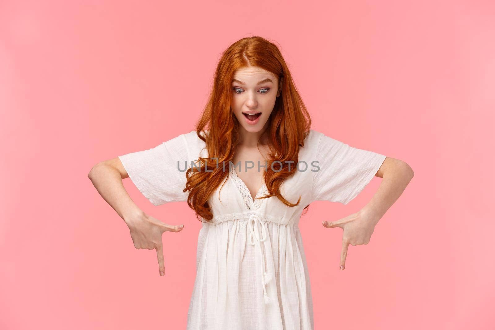 Shopping, promotion and people concept. Curious excited redhead female shopaholic, visit favorite store checking out something awesome, looking and pointing down with fascinated expression.