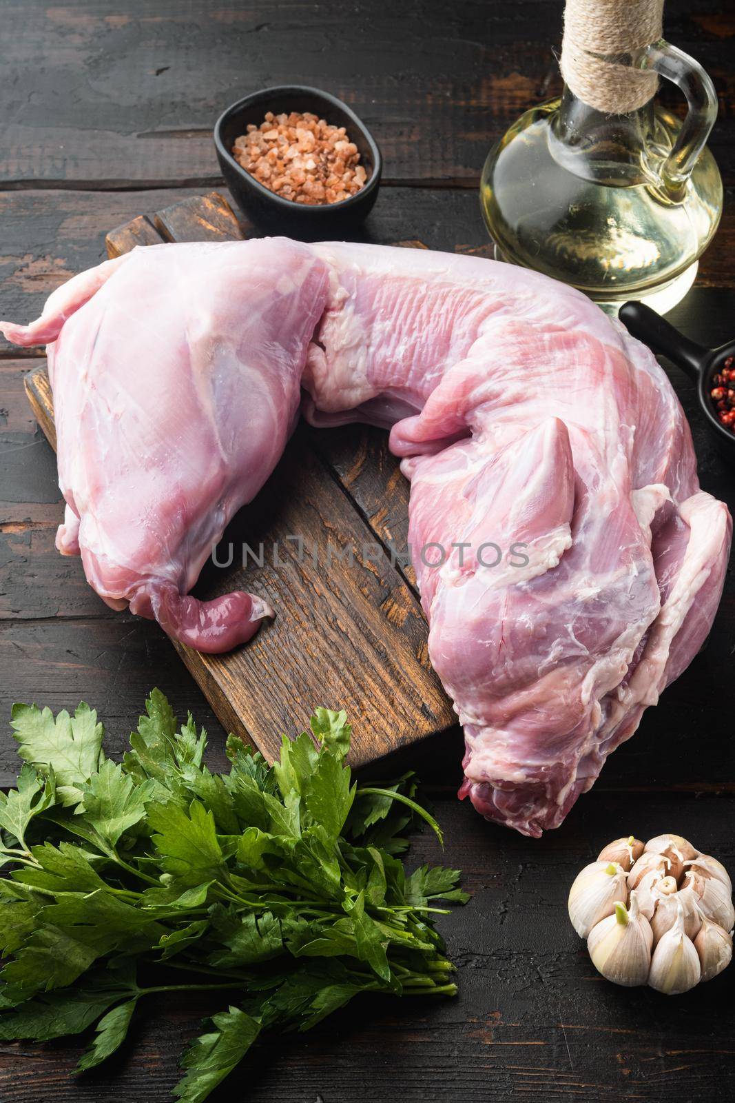 Fresh raw rabbit with olive oil, rosemary, peppers , on old dark wooden table background by Ilianesolenyi