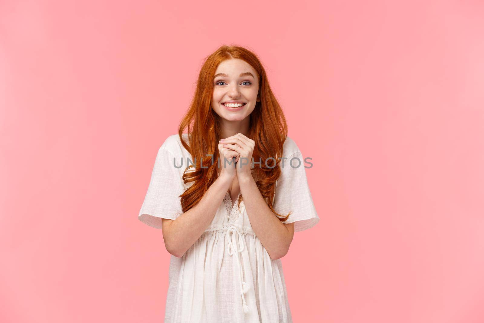 Waist-up portrait lovely happy and excited, redhead girl in cute dress, hold hands hopeful together and smiling with anticipation and delight, express aspiration and excitement, pink background.