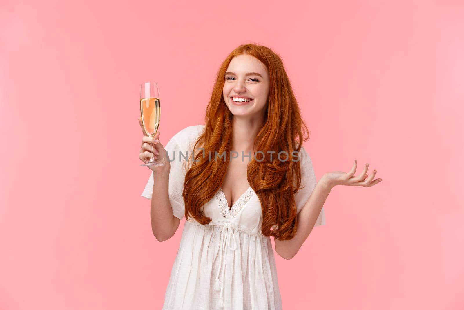 Lovely charismatic bride feeling happy and joyful, celebrating best day her lfie, looking camera amused, smiling raising glass champagne, drinking and partying, standing pink background.