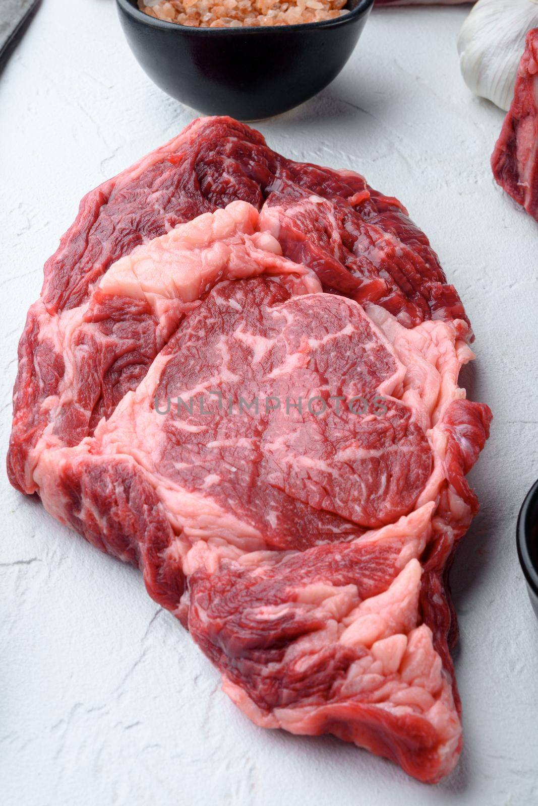 Raw fresh marbled meat Steak Ribeye Black Angus, on white stone background, top view flat lay by Ilianesolenyi