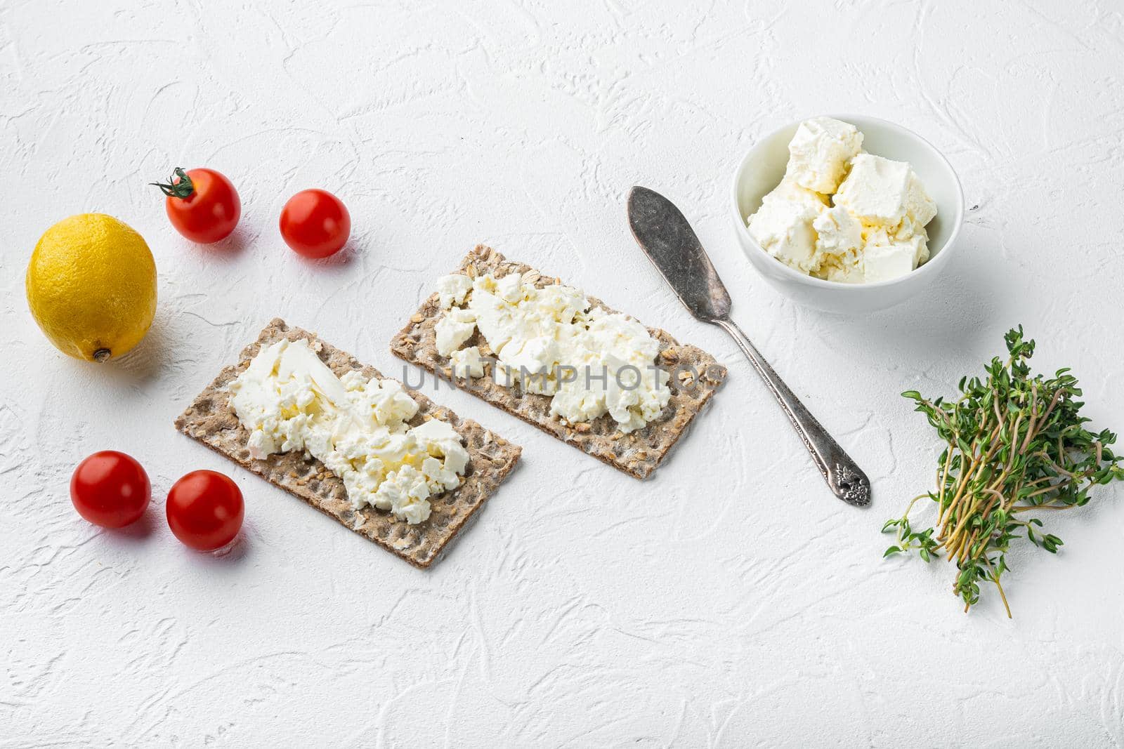 Curd sandwiches with fresh herbs. Crispbread toast with cottage cheese set, on white stone table background, with copy space for text
