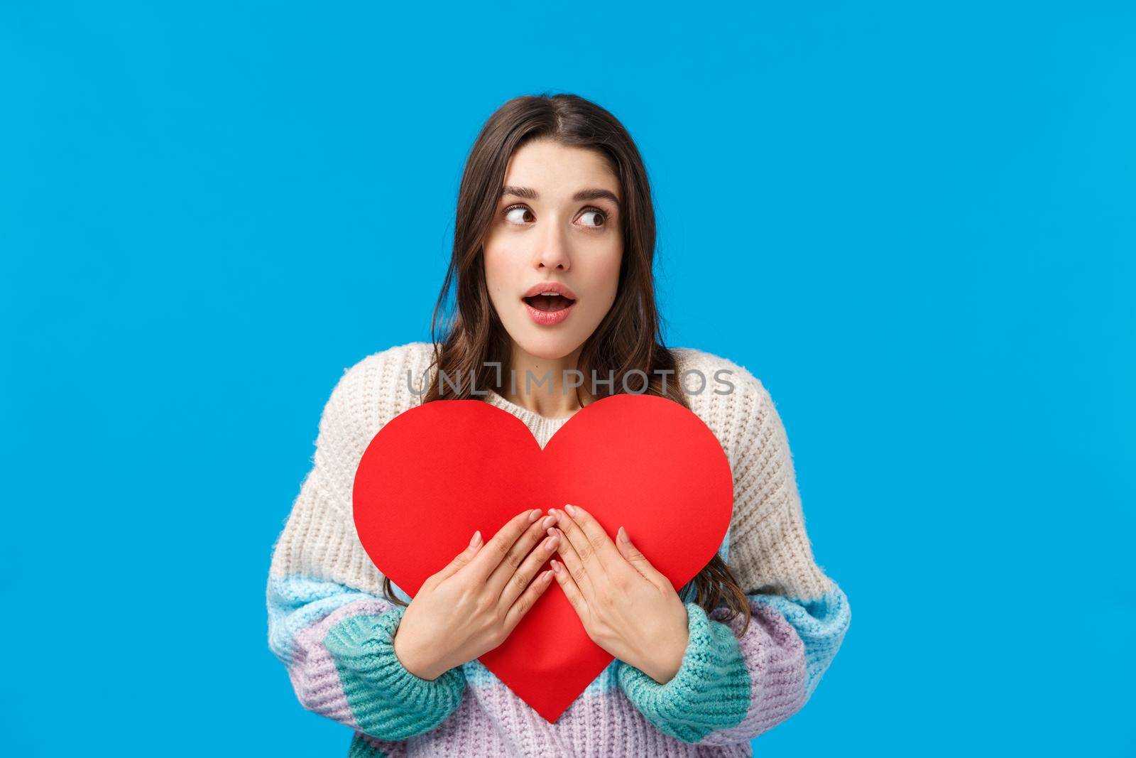 Waist-up portrait surprised and curious wondered caucasian woman dont know who prepared valentines-day gift for her, looking around open mouth amazed, embracing cute red cardboard heart by Benzoix