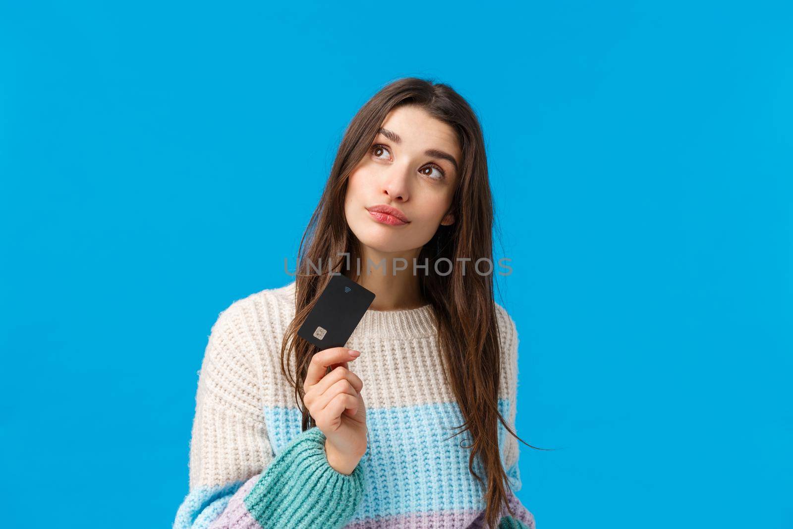 Shopping, discounts and winter holidays concept. Attractive dreamy girlfriend want prepare valentines surprise gift, thinking what buy, order online, holding credit card and thoughtful look up.