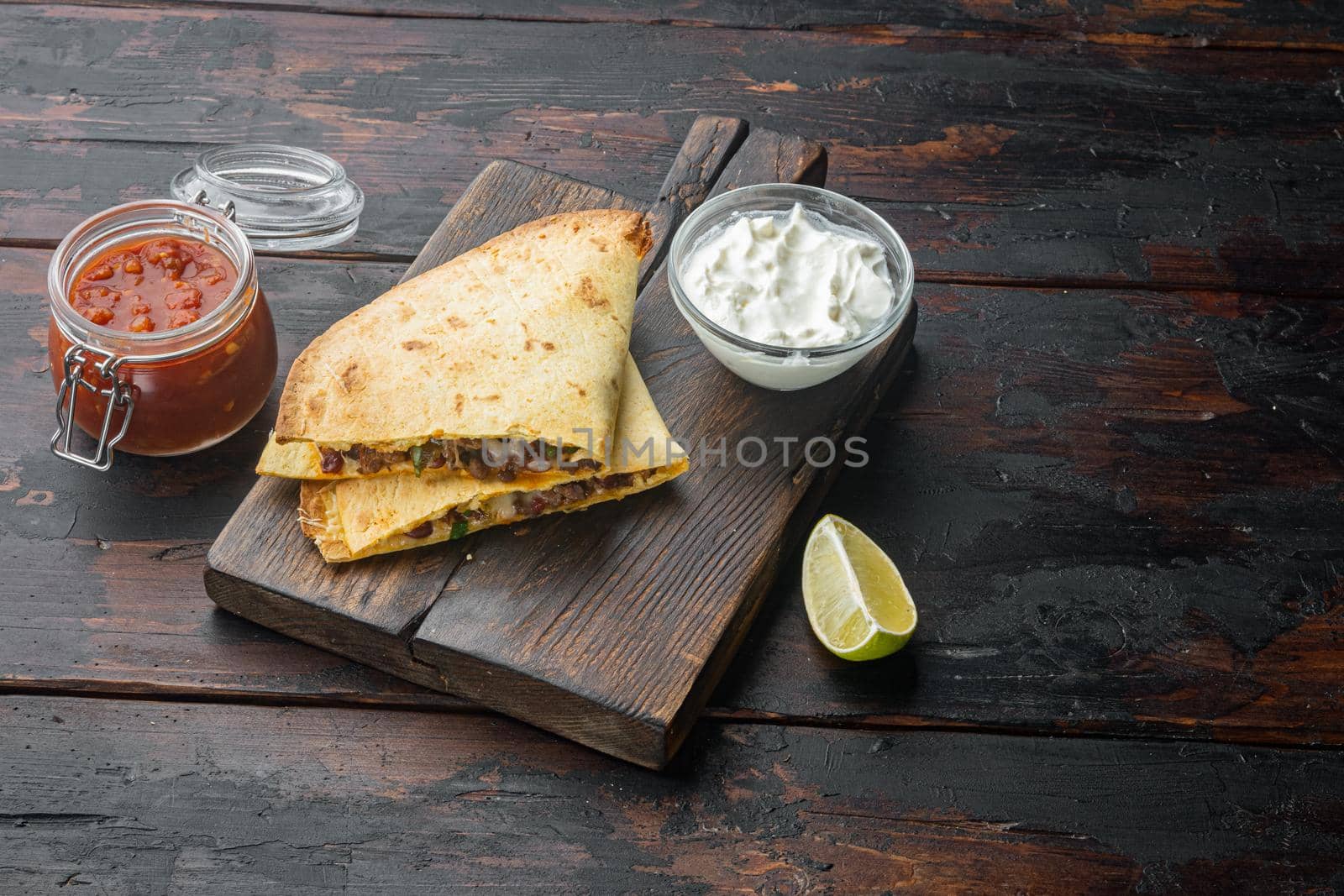 Quesadilla with chicken, cheese and vegetable, on old dark wooden table background with copy space for text