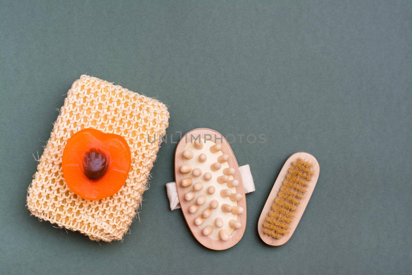 Body care. Washcloth, brush, massager and handmade soap on a green background. by Aleruana